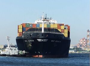 Beladenes Containerschiff mit Schlepper.